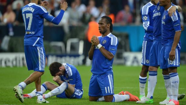 Enttäuschte Chelsea-Spieler nach einem Fußballspiel, darunter Didier Drogba kniend.