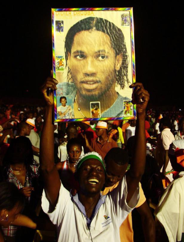 Ein Mann hält ein Poster von Didier Drogba in einer Menschenmenge hoch.