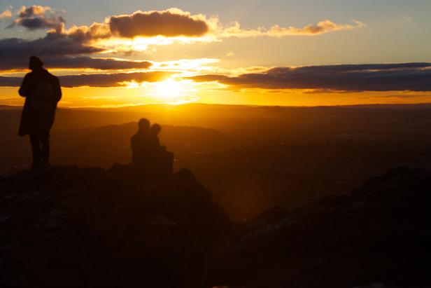 Menschen genießen den Sonnenuntergang auf einem Hügel.