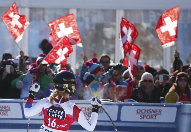 Eine Skirennläuferin jubelt vor einer Zuschauermenge mit Schweizer Flaggen.