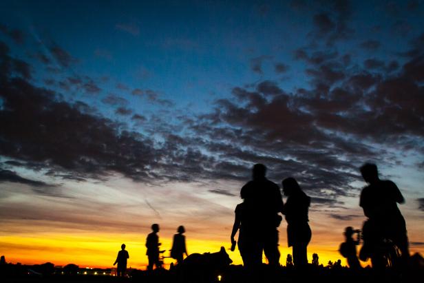 Silhouetten von Menschen vor einem farbenprächtigen Sonnenuntergang.