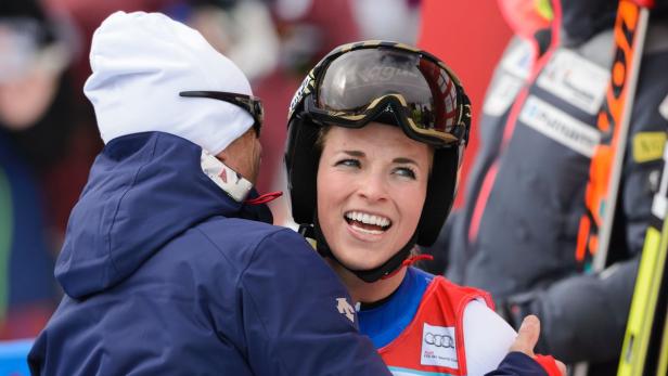 Eine Skirennläuferin umarmt einen Mann und lächelt.