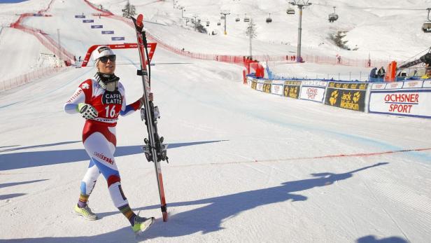 Eine Skirennläuferin im Schweizer Rennanzug steht mit ihren Skiern auf der Piste.