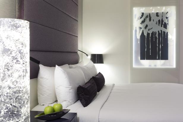 Ein modernes Schlafzimmer mit einem lila Kopfteil und einem abstrakten Kunstwerk.