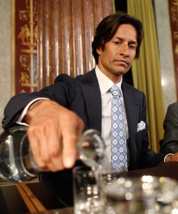 REUTERSFormer Austrian Finance Minister Karl-Heinz Grasser pours a glass of water as he waits for a session of an inquiry hearing (Untersuchungsausschuss) to begin in the parliament in Vienna, May 22, 2012. The investigative panel is looking into a series Ein Mann im Anzug gießt Wasser in ein Glas.