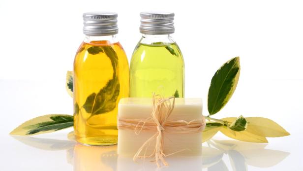 Zwei Flaschen mit Öl und ein Stück Seife mit einer Schleife auf einem weißen Hintergrund.