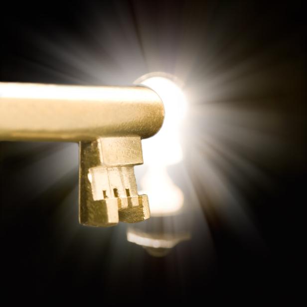 Ein goldener Schlüssel steckt in einem Schlüsselloch, durch das helles Licht scheint.