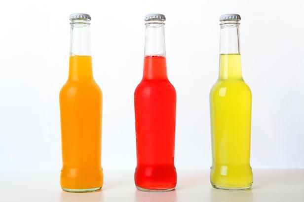 Drei Glasflaschen mit bunten Erfrischungsgetränken stehen nebeneinander.