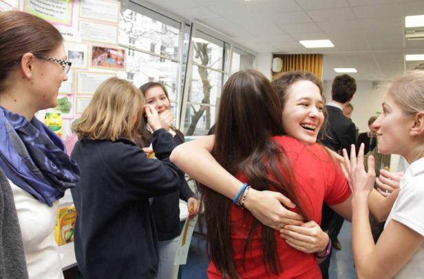 Eine Gruppe junger Frauen umarmt sich und lacht in einem hellen Raum.