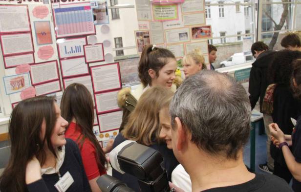 Eine Gruppe von Menschen steht vor einer Wand mit wissenschaftlichen Postern.
