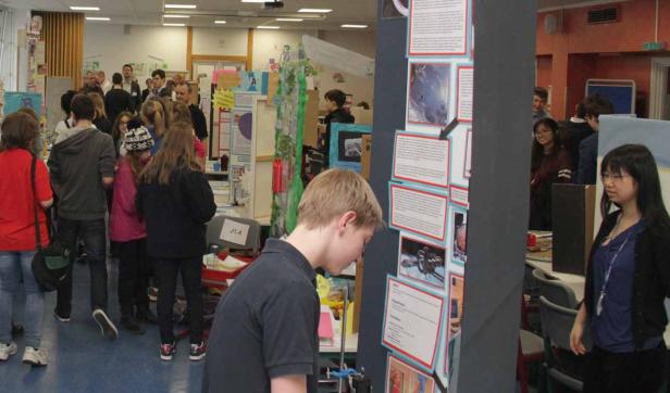 Eine Gruppe von Schülern betrachtet Projekte auf einer Wissenschaftsmesse.