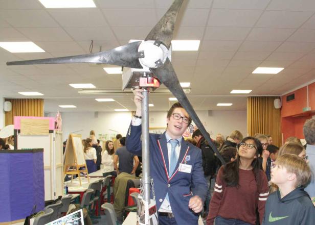 Ein junger Mann präsentiert ein Windrad auf einer Wissenschaftsmesse.