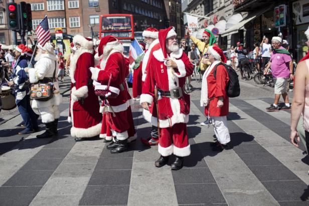 Eine Gruppe von Menschen, verkleidet als Weihnachtsmänner, steht auf einer Straße.