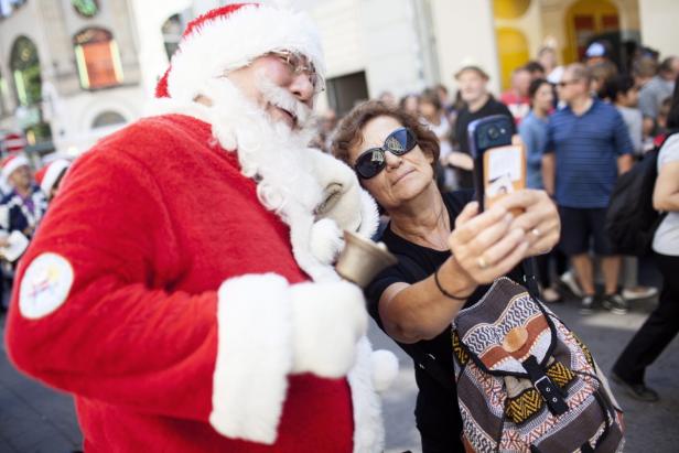 Eine Frau macht ein Selfie mit einem Weihnachtsmann in der Öffentlichkeit.