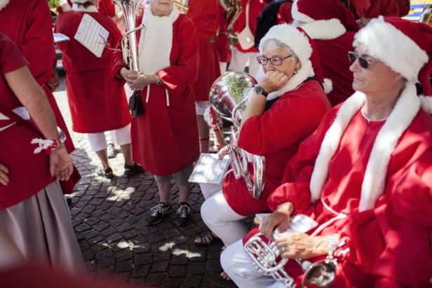 Eine Gruppe von Menschen in Weihnachtsmannkostümen mit Musikinstrumenten.