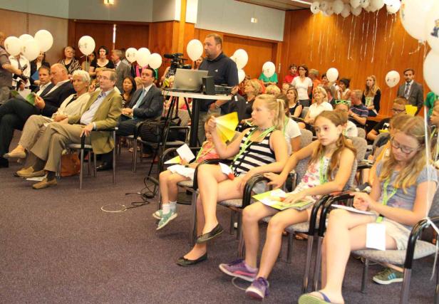 Eine Gruppe von Erwachsenen und Kindern sitzt in einem Raum mit weißen Ballons.