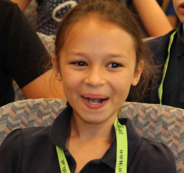 Ein lächelndes junges Mädchen sitzt auf einem Stuhl.