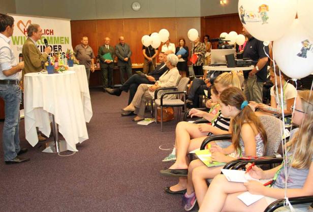 Eine Gruppe von Kindern sitzt bei einer Veranstaltung in einem Publikum.