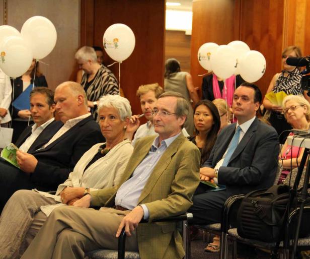 Eine Gruppe von Menschen sitzt bei einer Veranstaltung mit weißen Ballons im Publikum.