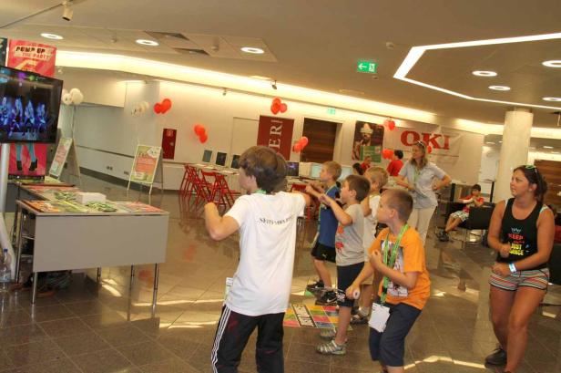 Eine Gruppe Kinder tanzt vor einem Bildschirm, während Erwachsene zusehen.