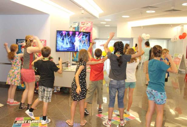 Eine Gruppe Kinder tanzt vor einem Bildschirm zu „Just Dance“.