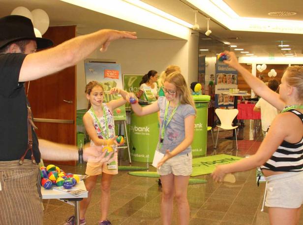 Mädchen lernen von einem Mann, wie man mit Bällen jongliert.