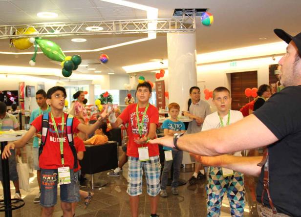 Eine Gruppe von Kindern jongliert mit Bällen in einem hellen Raum.