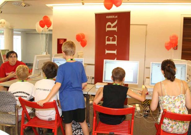 Kinder sitzen an Computern bei einer Veranstaltung von Kurier.at.