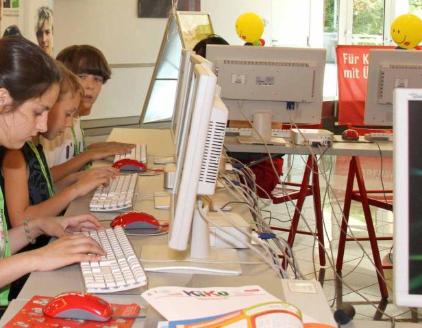 Eine Gruppe Kinder sitzt an Computern und tippt auf Tastaturen.
