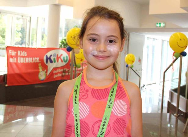 Ein junges Mädchen mit Sonnencreme im Gesicht lächelt in die Kamera.