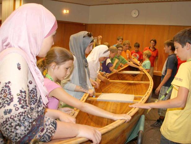 Eine Gruppe von Kindern baut gemeinsam ein Holzboot.