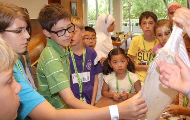 Eine Gruppe Kinder betrachtet ein Stück Gittergewebe.