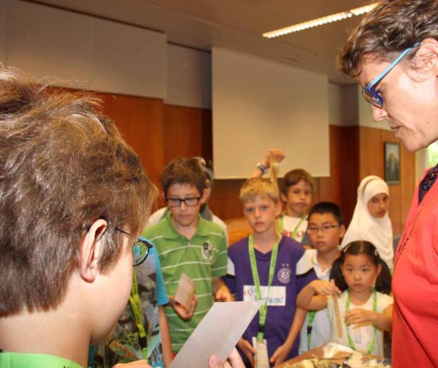 Eine Gruppe von Kindern arbeitet mit einer Lehrerin an einem Projekt.