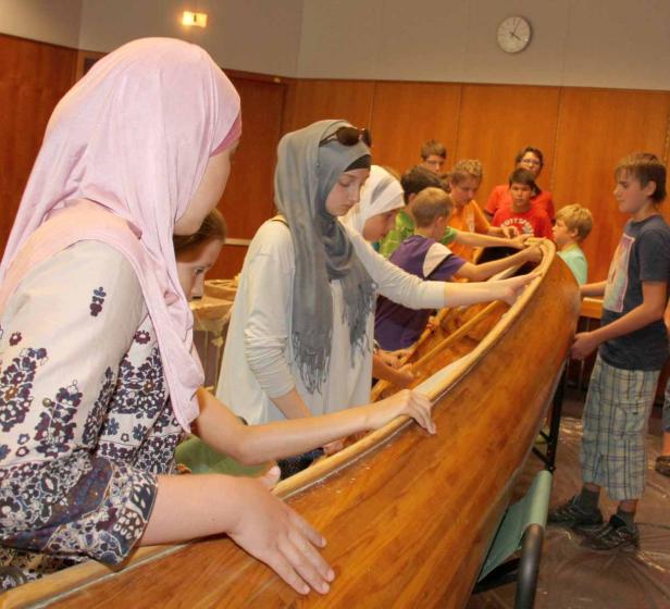 Eine Gruppe von Jugendlichen baut gemeinsam ein Holzboot.