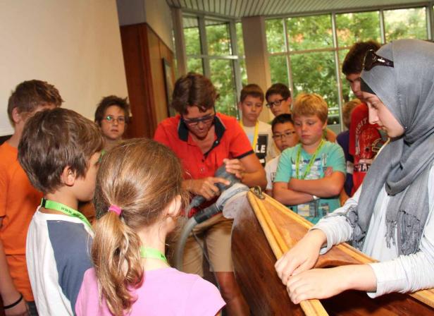 Eine Gruppe von Kindern beobachtet, wie ein Mann ein Holzboot schleift.