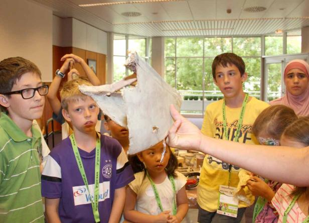 Eine Gruppe von Kindern betrachtet ein Objekt aus Pappmaché.