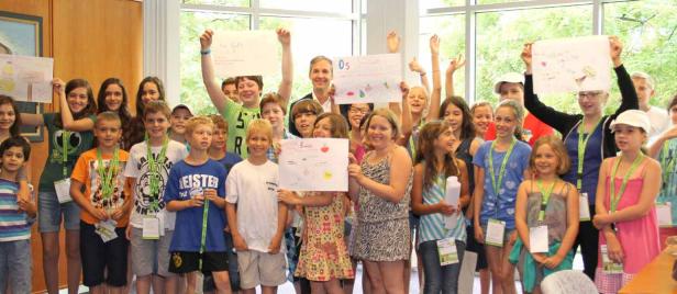 Eine Gruppe Kinder präsentiert selbstgemalte Bilder mit Obst und Gemüse.