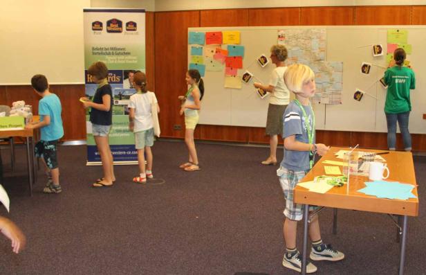 Kinder und Betreuer arbeiten an einer Weltkarte mit Fähnchen.