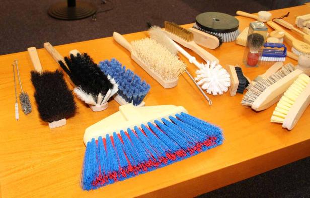 Verschiedene Bürsten und Besen liegen auf einem Tisch.