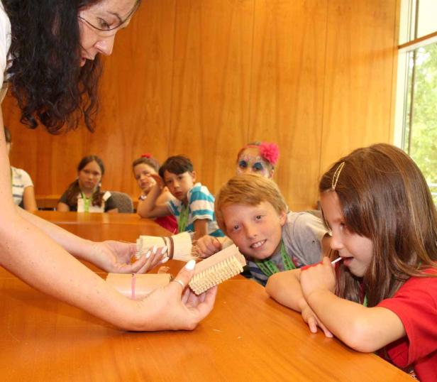 Eine Frau zeigt einer Gruppe von Kindern Bastelmaterialien.