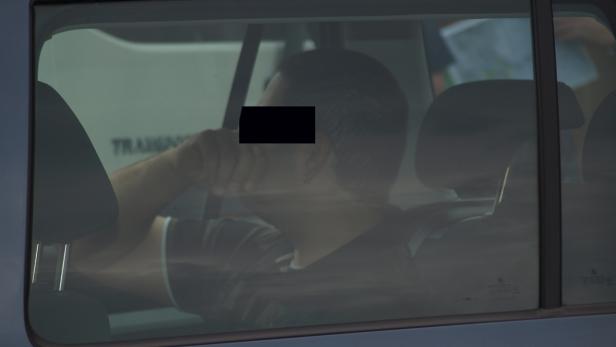 Ein Mann sitzt in einem Auto und blickt aus dem Fenster.