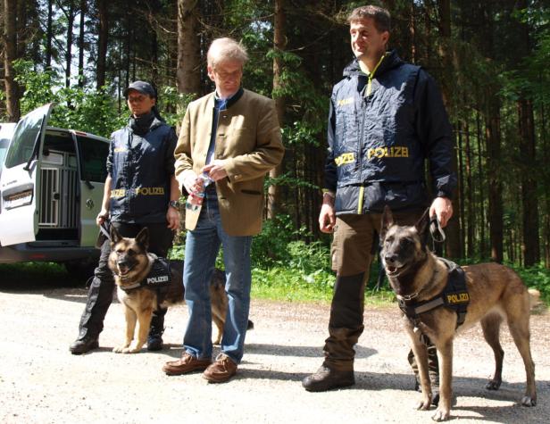 Zwei Polizisten und eine Polizistin mit ihren Diensthunden im Wald.