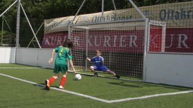 Ein Junge schießt einen Fußball auf ein Tor, das von einem anderen Jungen gehütet wird.