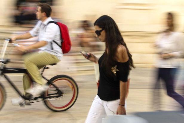 Ein Mann fährt Fahrrad, während eine Frau auf ihr Handy schaut.