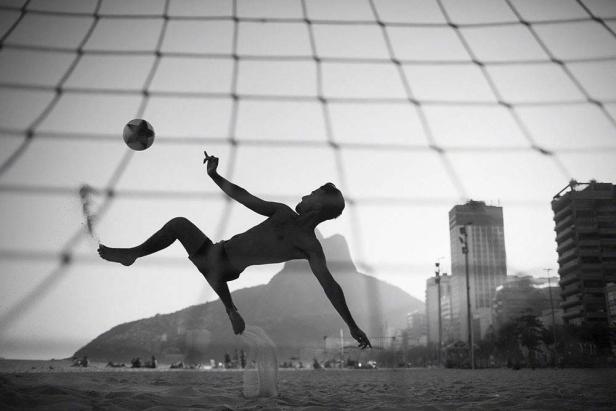 Ein Mann macht einen Fallrückzieher mit einem Fußball am Strand von Rio de Janeiro.