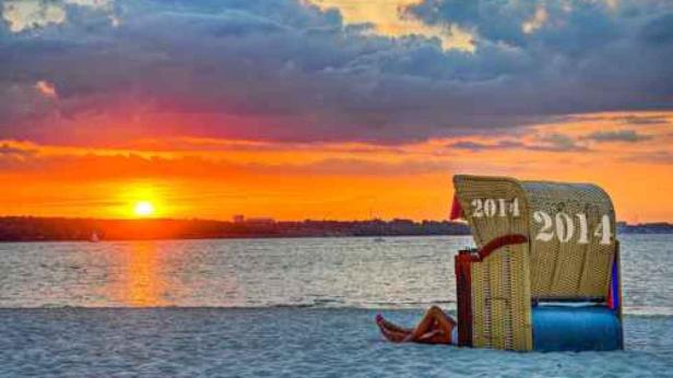 … Ein Strandkorb mit der Aufschrift „2014“ am Strand bei Sonnenuntergang.