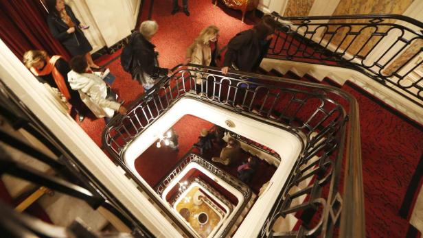 Visitors walk up the stairs as they visit the Hote Blick von oben auf ein Treppenhaus mit rotem Teppich und mehreren Personen.