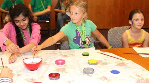 Kinder bemalen sich gegenseitig mit bunten Farben.