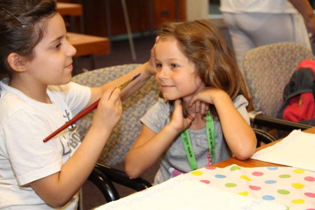Ein Mädchen bemalt das Gesicht eines anderen Mädchens mit einem Pinsel.