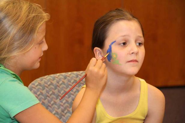 Ein Mädchen bekommt eine Gesichtsbemalung.